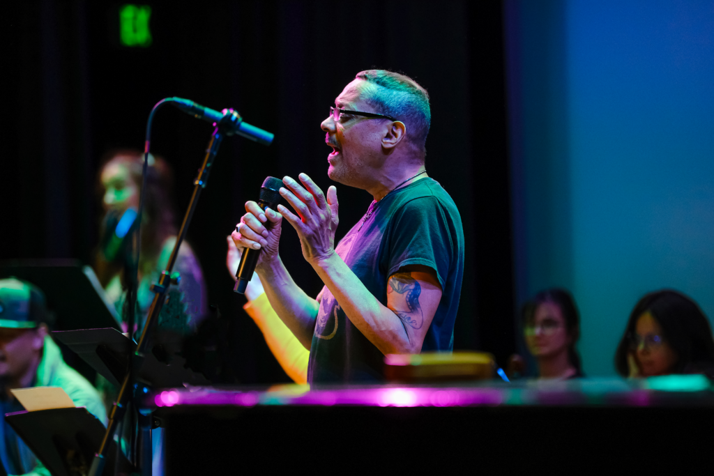 Participant Gary Nelson sings into a microphone with his hands raised