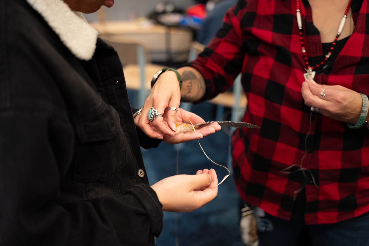 A workshop participant receives crafting materials from a Teaching Artist.