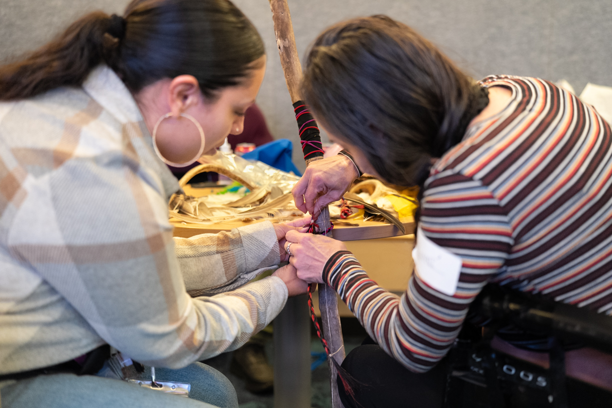 Participant craft together using sticks, colored leather, beads, and other materials at PwA's 