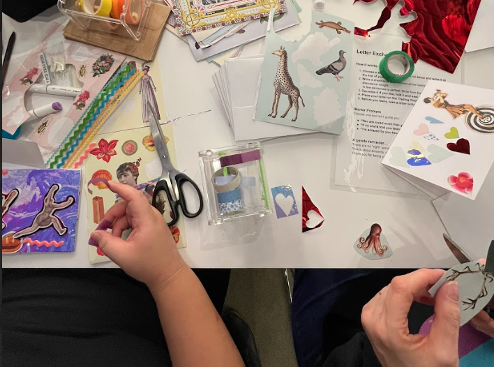 Arial view close up on two people working at a table full of stickers and collage supplies