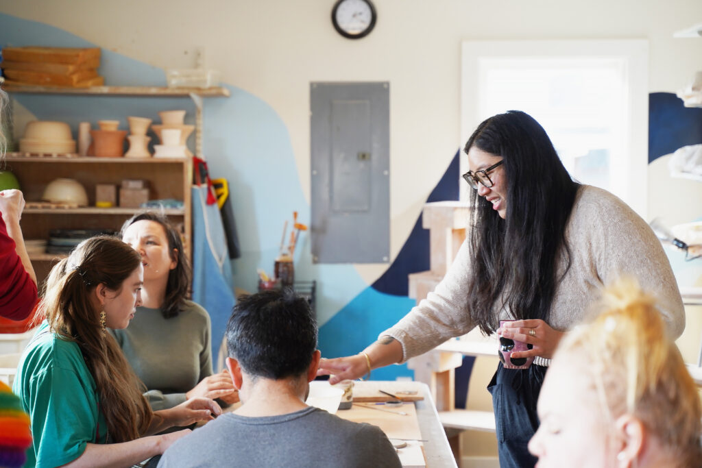 A Teaching Artist helps participants during a pottery class.