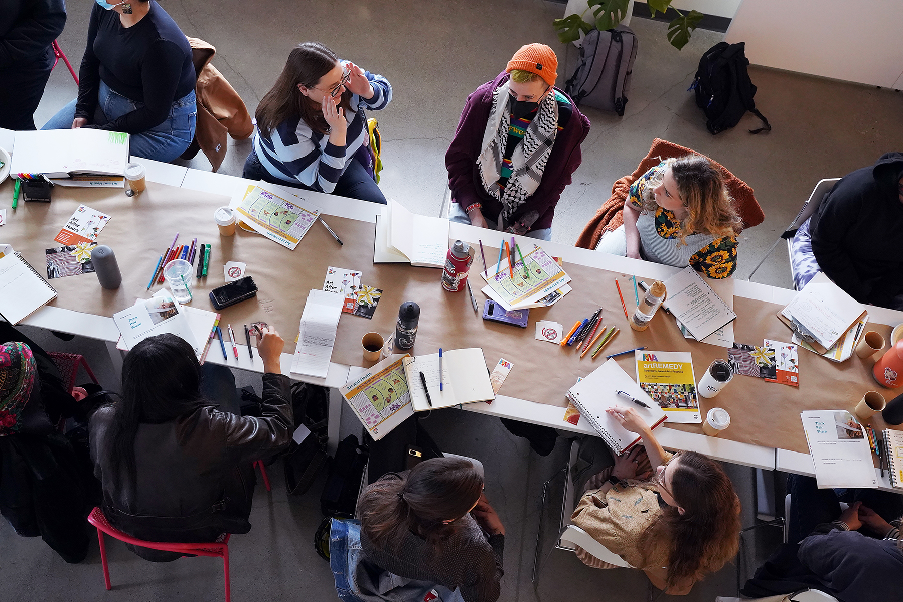 Participant in PwA's artREMEDY training sit and talk together at a communal table.