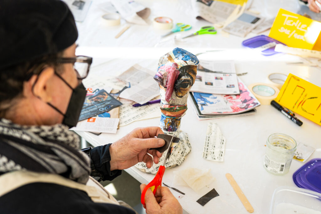 Participant Michael cuts a magazine piece for his papier mache sculpture
