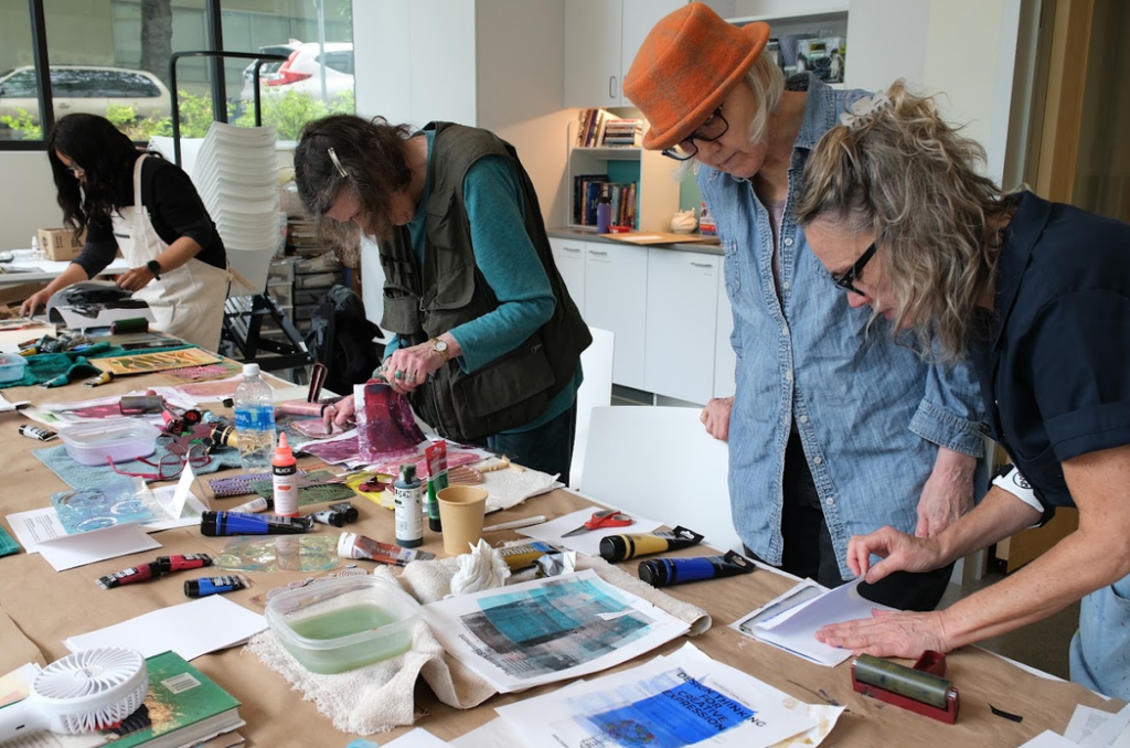 four people leaning over a table making art in class
